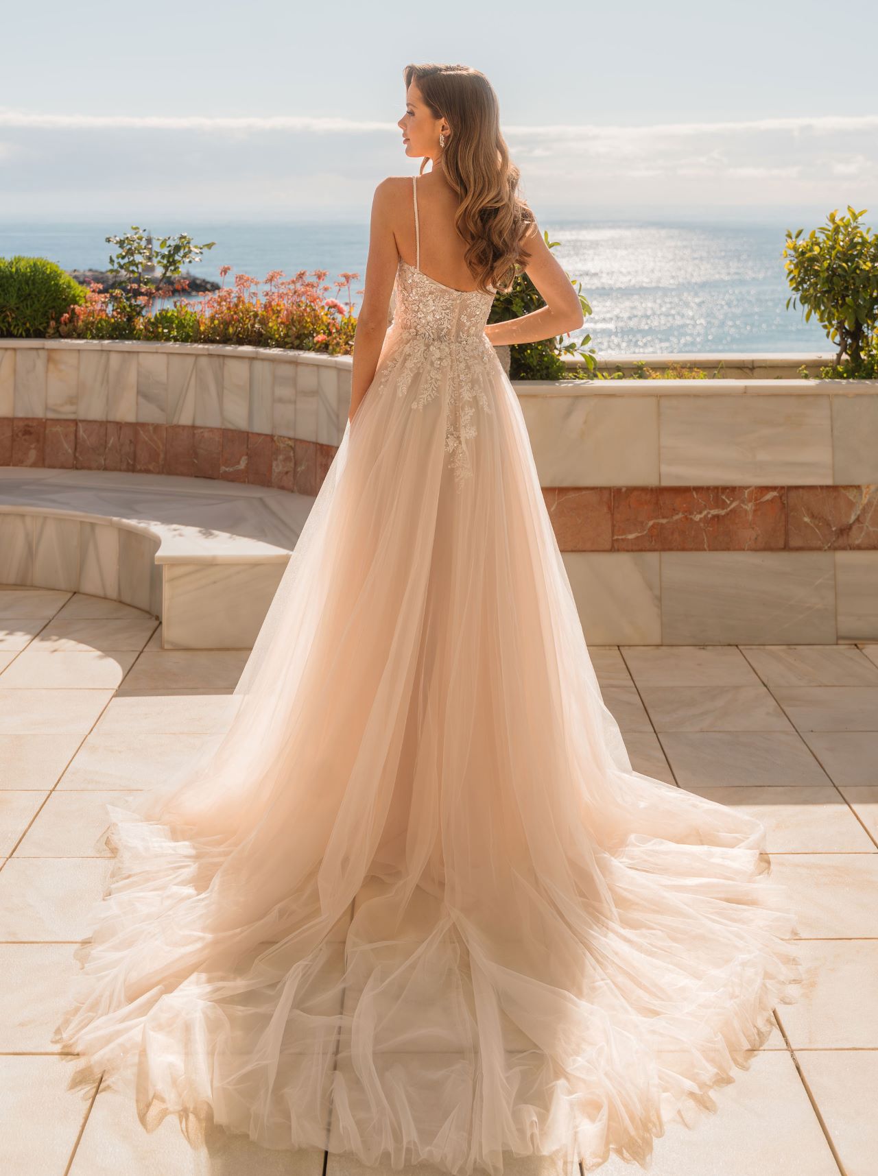 Blush A-Linien Hochzeitskleid mit floraler Spitze und hohem Schlitz – romantisches Tüll Wedding Dress für moderne Bräute, im Sonnenlicht fotografiert.