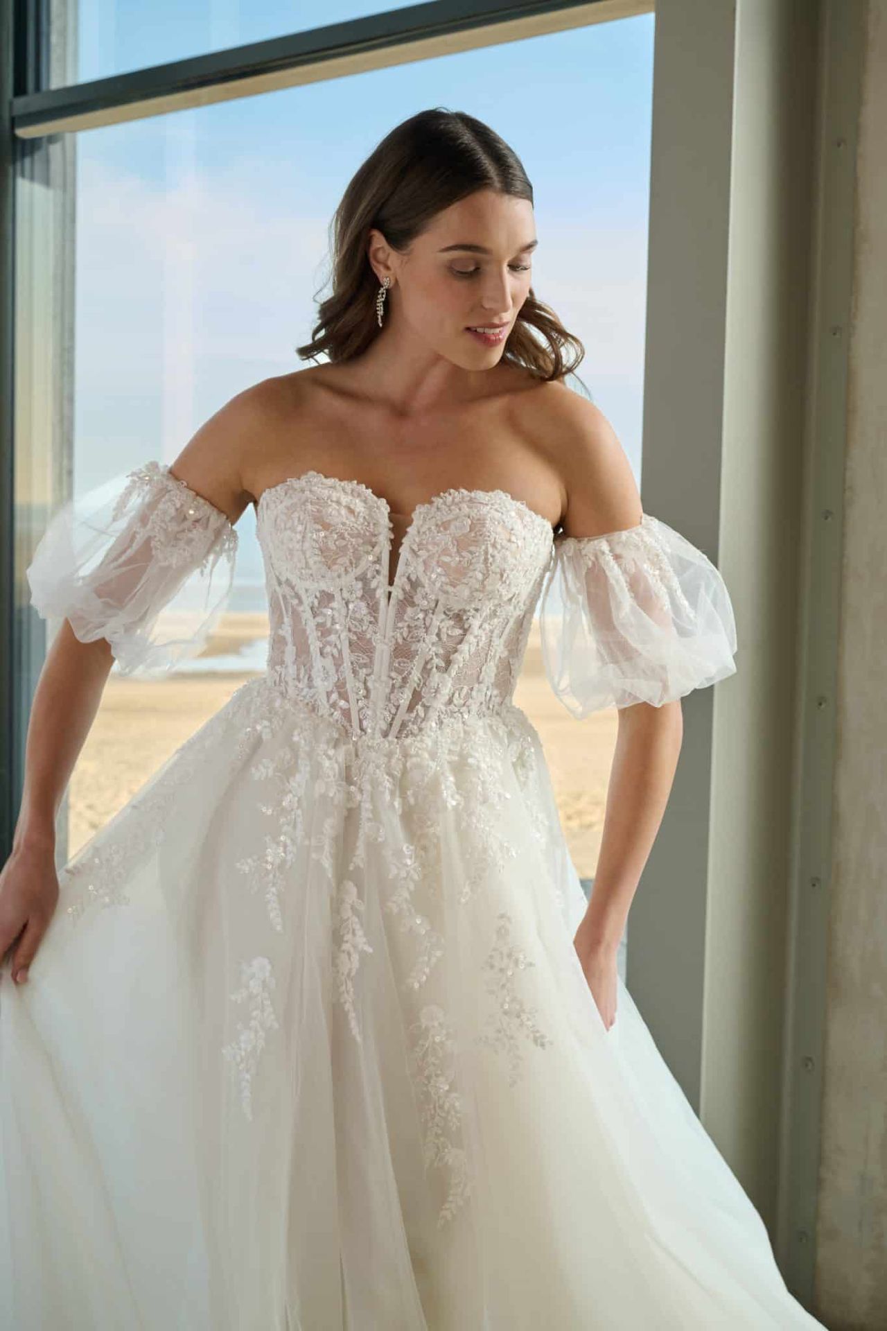 Romantisches A-Linien-Brautkleid mit Off-Shoulder-Puffärmeln, transparenter Spitzen-Corsage, floralen Applikationen und Tüllrock – Weddingdress bei Brautfashion in Sins