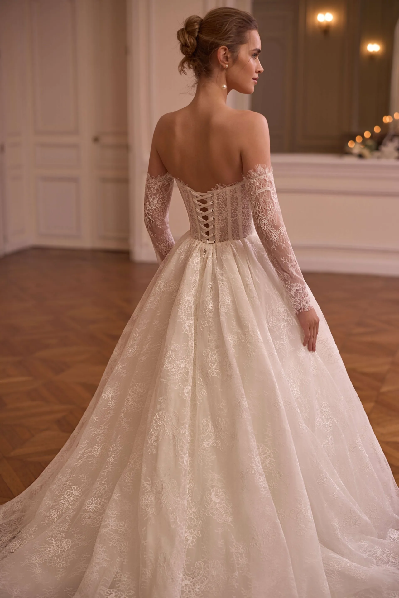 Romantisches Brautkleid mit Off-Shoulder-Ausschnitt, langen Spitzenärmeln, transparenter Corsage und floralem Spitzenrock – Weddingdress bei Brautfashion in Sins
