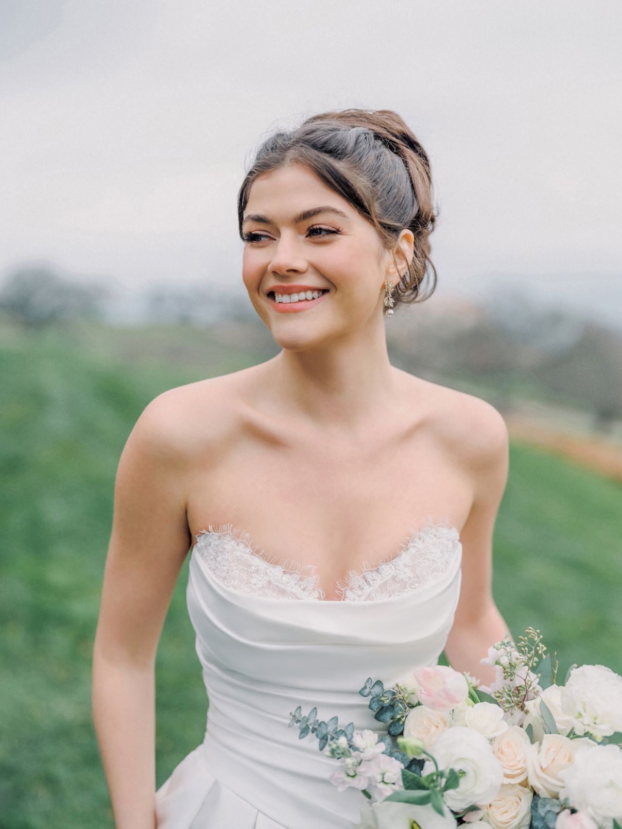 Clean-Chic-Brautkleid mit trägerloser Drapierung, feiner Spitze, Basque Taille und romantischem Brautstrauss – Weddingdress bei Brautfashion in Sins