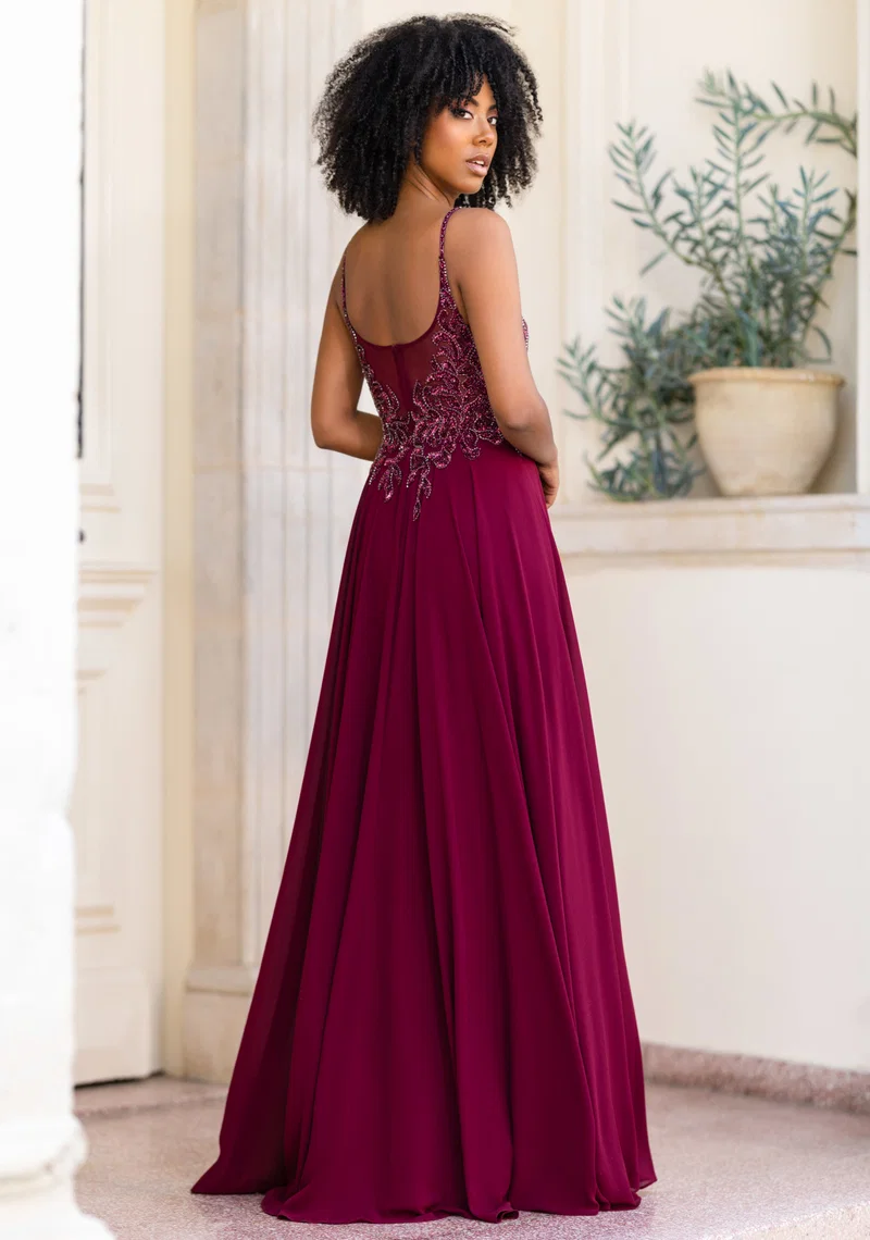 Bordeauxfarbenes Festkleid mit Spaghettiträgern, V-Ausschnitt, transparentem Spitzenoberteil, Perlen- und Glitzerdetails sowie fliessendem Rock – Festmode bei Brautfashion in Sins