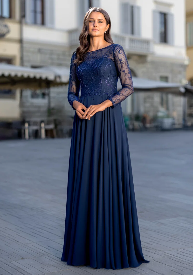 Elegantes dunkelblaues Festkleid mit langen transparenten Spitzenärmeln, Perlen- und Glitzerdetails, Rundhalsausschnitt und fliessendem Rock – Festmode bei Brautfashion in Sins