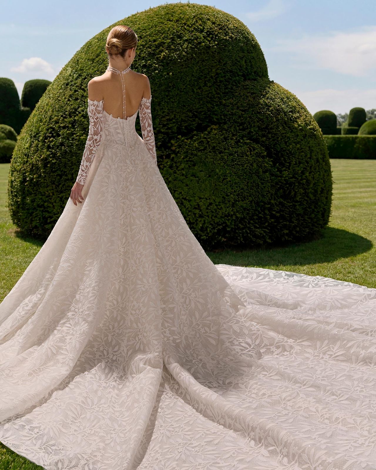 Romantisches Hochzeitskleid mit Off-Shoulder-Spitzenärmeln, floraler All-over Lace, herzförmigem Ausschnitt, voluminöser A-Linie, tiefem Rücken und langer Schleppe – Vorder- und Rückenansicht bei Brautfashion in Sins