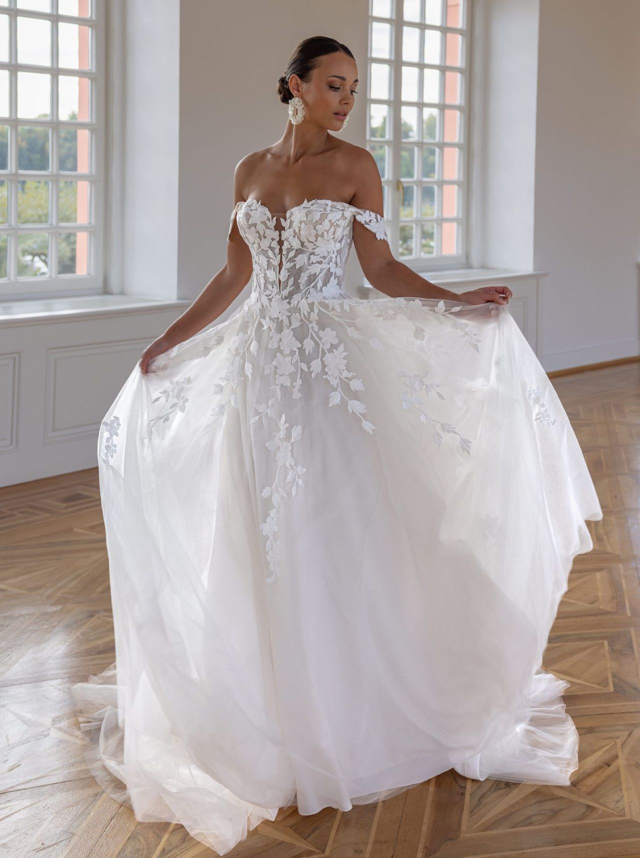 Romantisches Hochzeitskleid mit off-shoulder Trägern, floraler Spitzen-Corsage, herzförmigem Ausschnitt, fliessendem Tüllrock und langer Schleppe – Vorder- und Rückenansicht bei Brautfashion in Sins