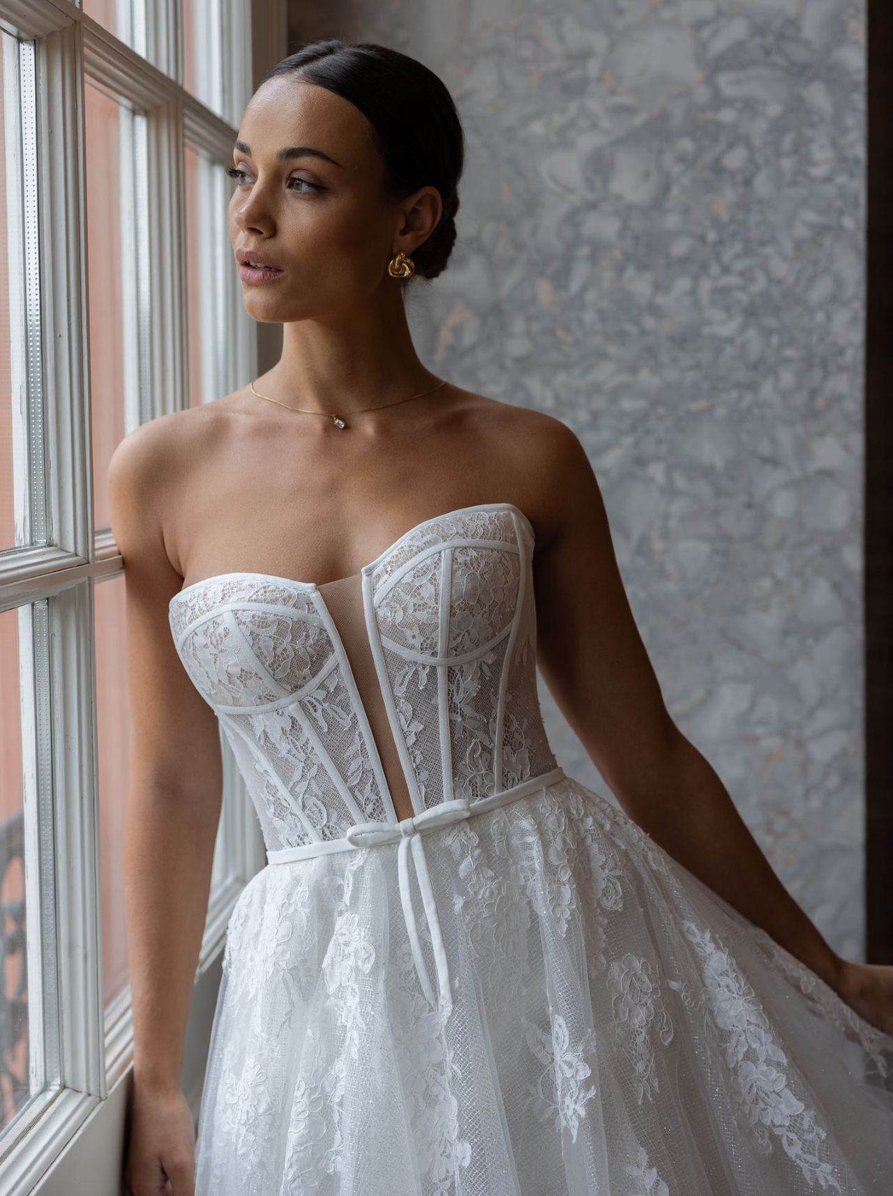 Romantisches Hochzeitskleid mit trägerloser Spitzen-Corsage, feinem Taillenband, voluminösem Tüllrock, transparentem Corsagenrücken und langer Schleppe – Vorder- und Rückenansicht bei Brautfashion in Sins