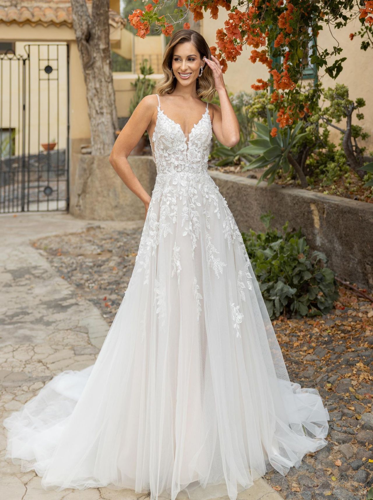 Romantisches Hochzeitskleid mit Spaghettiträgern, transparenter Spitzen-Corsage, tiefem V-Ausschnitt, offenem Rücken, fliessendem Tüllrock und langer Schleppe – Vorder- und Rückenansicht bei Brautfashion in Sins