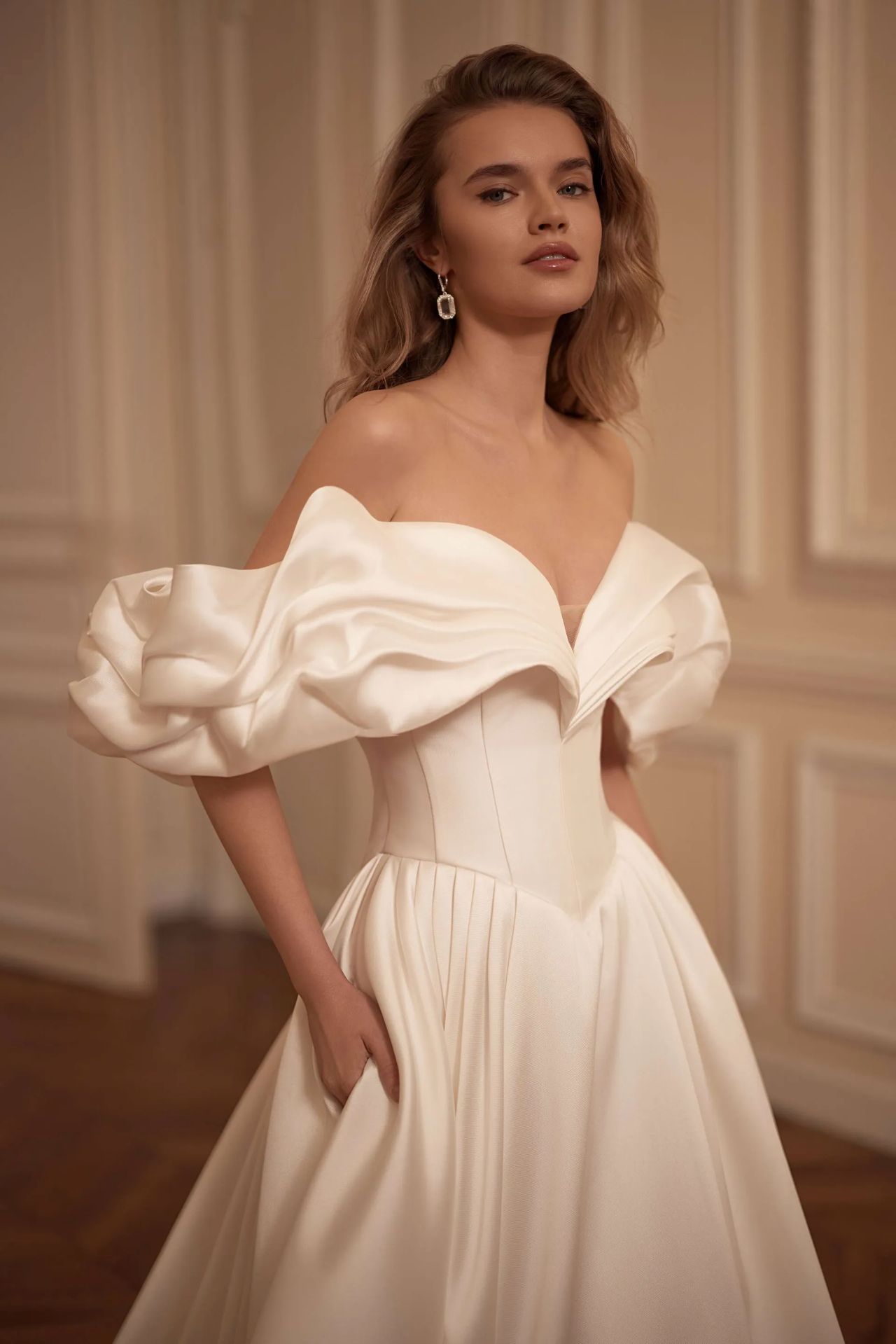 Cleanes Hochzeitskleid mit Off-Shoulder-Statement-Ärmeln, drapierter Corsage, Basque-Taille, voluminösem Rock, Knopfleiste und moderner Prinzessinnen-Silhouette – Vorder- und Rückenansicht bei Brautfashion in Sins