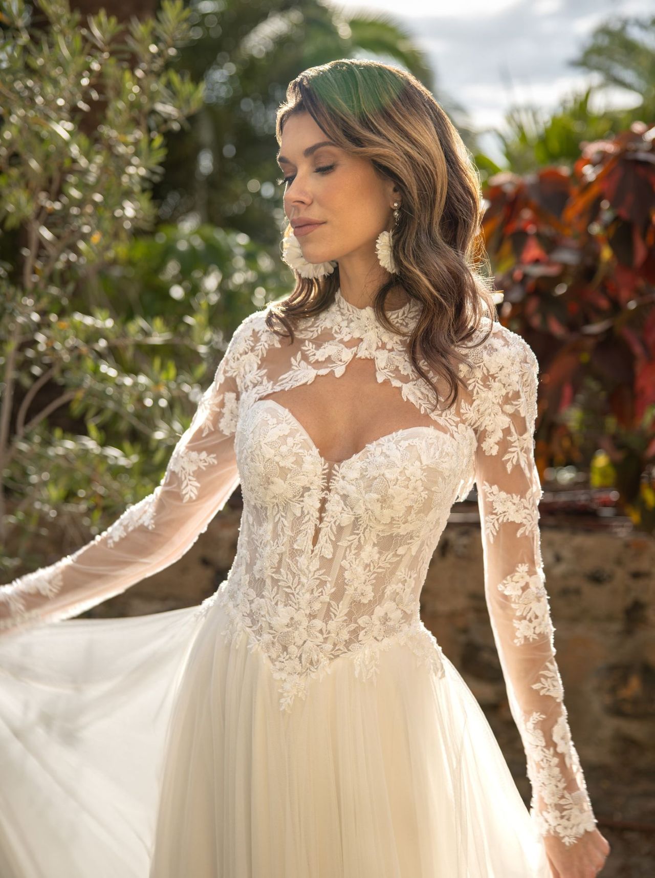 Romantisches Hochzeitskleid mit trägerloser Spitzen-Corsage, abnehmbarer Spitzenjacke, langen Ärmeln, offenem Rücken, fliessendem Tüllrock und langer Schleppe – Brautmode bei Brautfashion in Sins